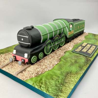 sculpted birthday cake of the flying scotsman train set in a sceneic edible display. Handpainted details