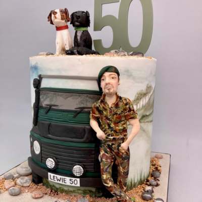 Bespoke triple layered birthday cake featuring handmade figure and 2D decoration of a landrover vehicle & two hand modelled dogs with hand painted scene