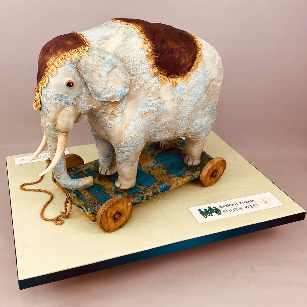 Hand sculpted pull along toy elephant cake. This cake featured textured surfaces to give that really well loved aged feel to the surface. Created in aid of a charity event for Childrens Hospice South West