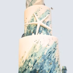 A two tiered fondant wedding cake with edible coastal details. Displayed at Talland Bay Hotel
